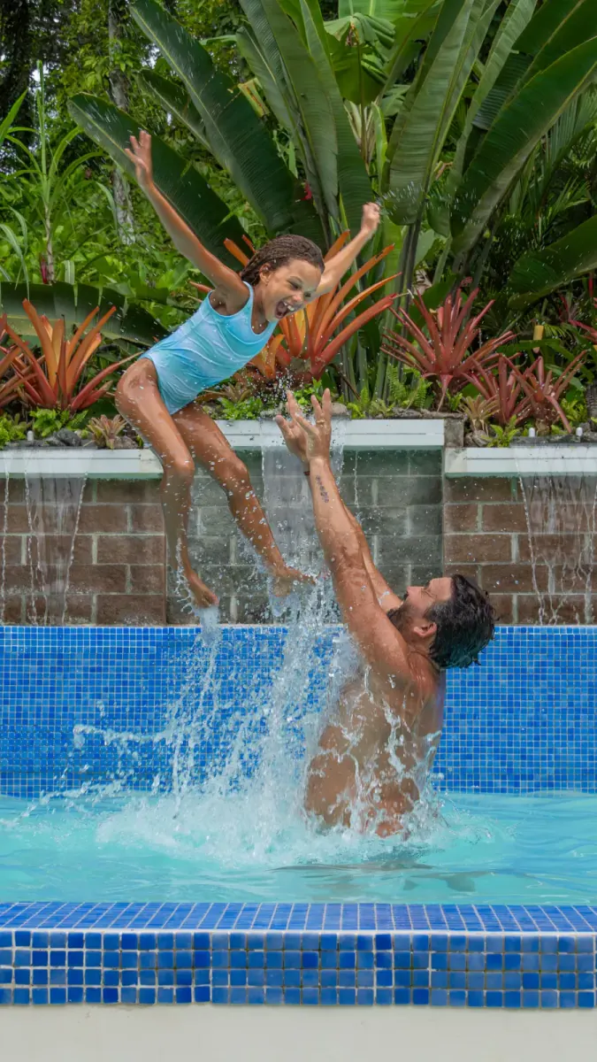 Man splashing in the pool beside the waterfall wall
