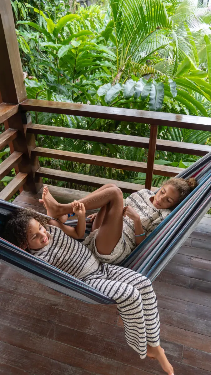 Two children relaxing in a hammock on a wooden deck